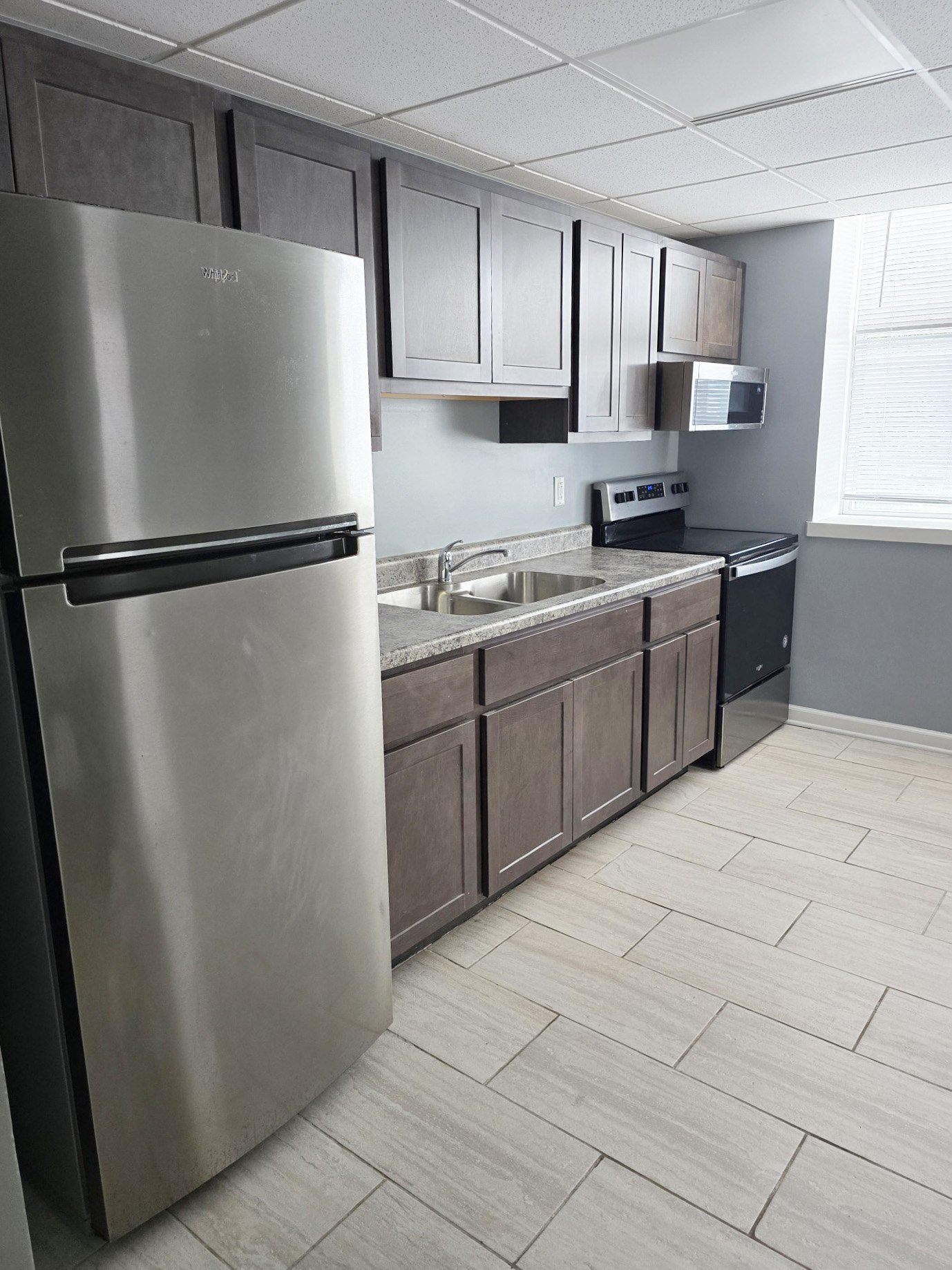 A kitchen with a stainless steel refrigerator and wooden cabinets.